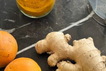 Bienfaits du jus de citron et fruits: citrons, prunes jaunes et gingembre frais sur plan de travail, pot de miel et pichet d’eau à côté. Remède digestion citron.